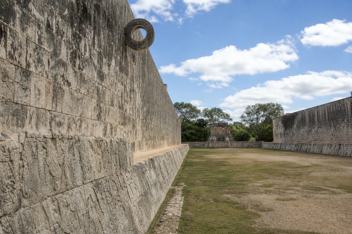 The Great Ball Court at Chichen Itza with visitors walking the stone playing field on a private tour